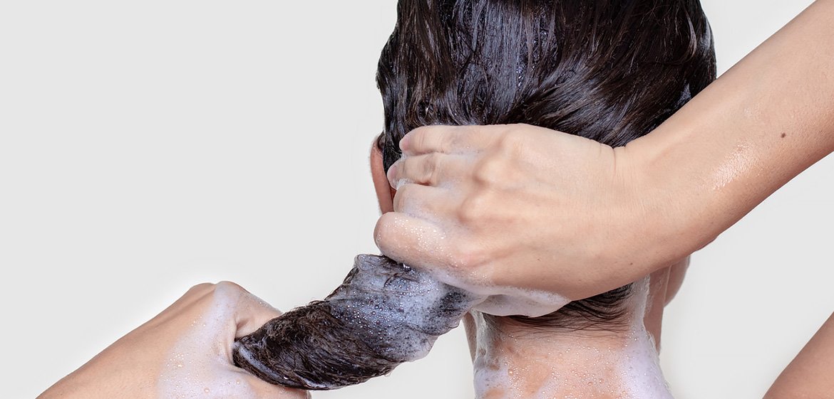 Frau wringt ihre nassen und shampoonierten Haare aus.